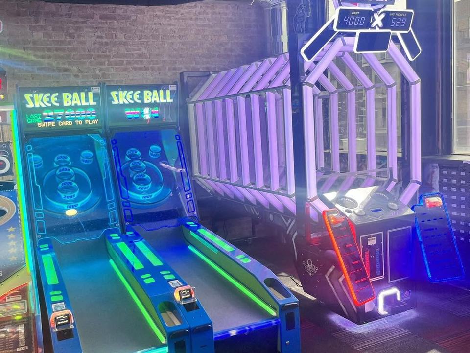 Skee-ball lanes glowing blue and purple under neon.