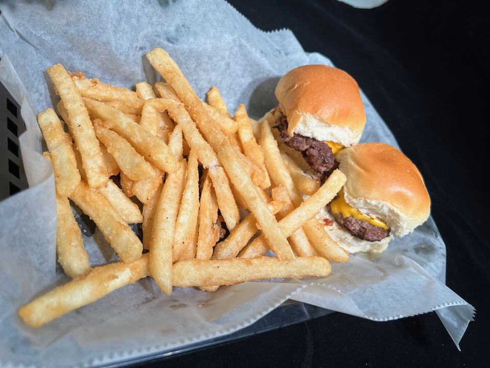 Kids' slider basket: two cheeseburger sliders with a heap of seasoned fries on paper.