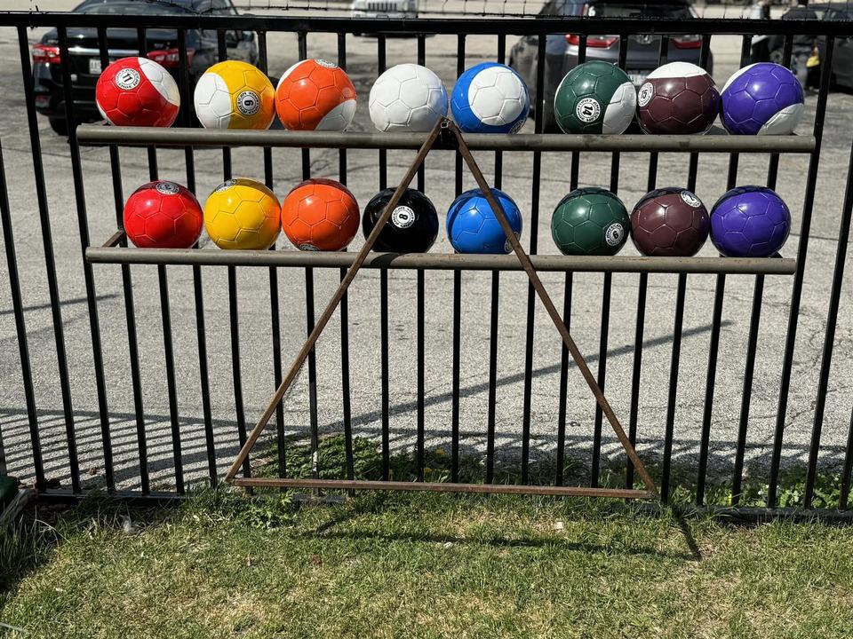 A rack of lawn-size colored pool balls hung on the iron fence.