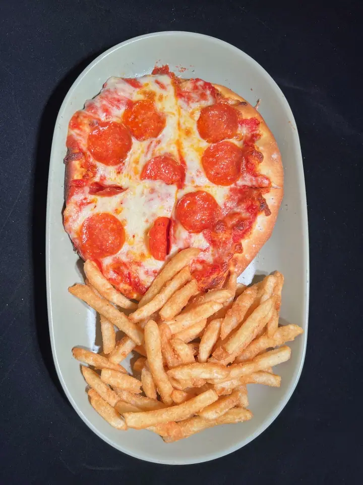 I Am Not Hungry: a mini pepperoni pizza with a side of fries on an oval plate, shot from above.
