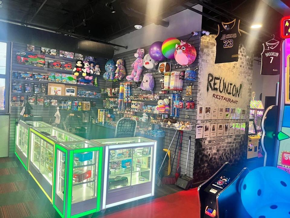 The prize counter: lit glass cases of toys, a wall of plush prizes and the Reunion Restaurant sign.