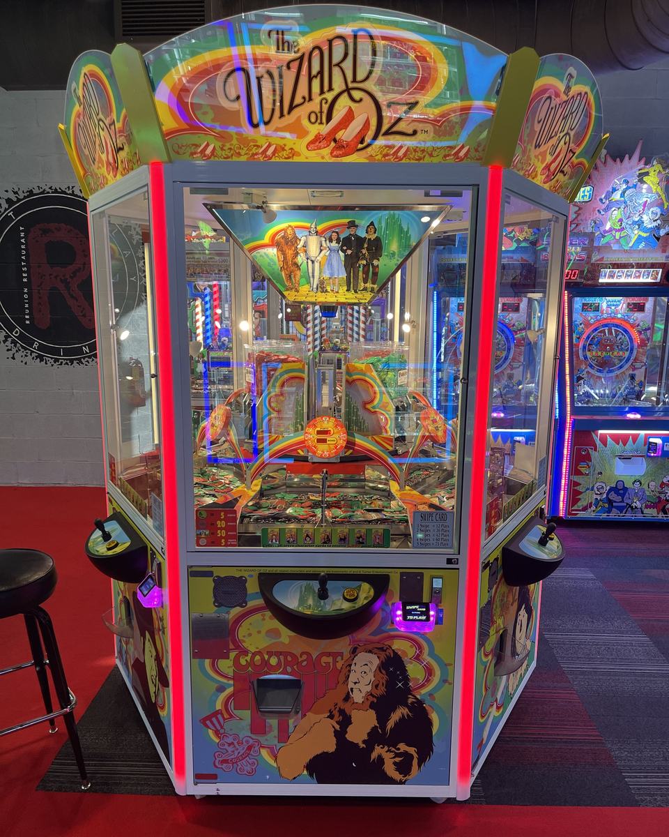 A Wizard of Oz coin pusher with a red-lit frame on the arcade floor.