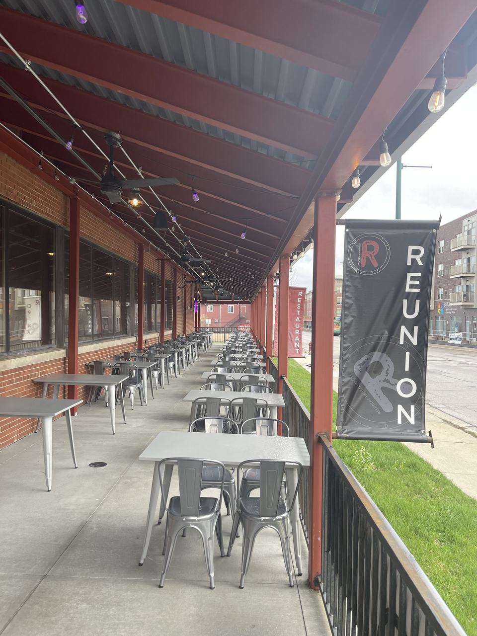 The covered patio with a row of metal tables and a black REUNION banner on the post.